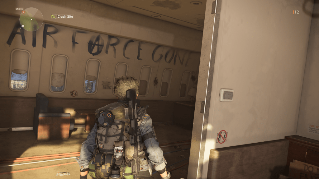 Player avatar standing in the remains of Air Force One, the phrase "Air Force One" spraypainted on the wall of the cabin and later edited to read "Air Farce Gone." The A in "farce" is drawn to look like the Anarchy symbol.